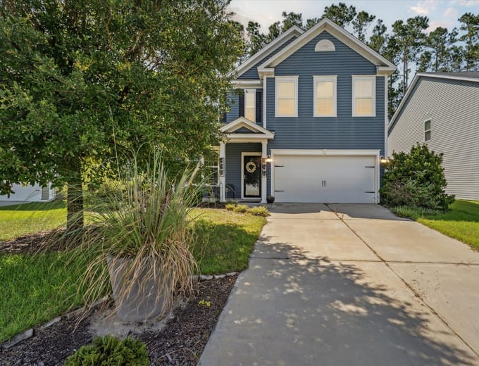 Two-story Pooler, GA home at dusk with warm interior lighting and a two-car garage